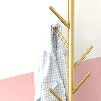 A gold coat rack with a blue and white checkered shirt hanging on it, against a white and pink background.