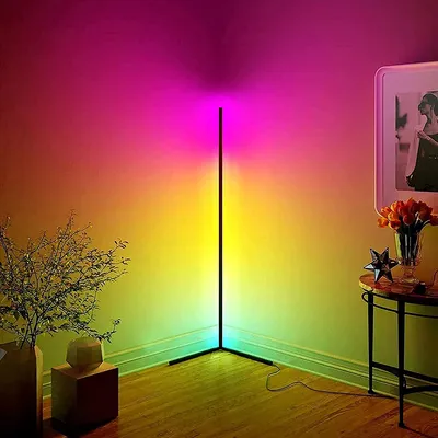 A corner lamp with RGB lighting casts colorful light on the walls and floor of a room. There are decorative items in the foreground.