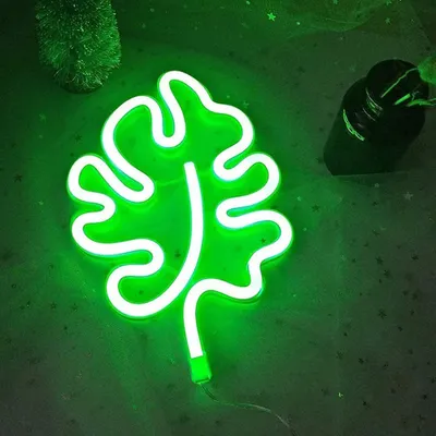 A green leaf-shaped neon light is displayed on a dark green, star-patterned background.