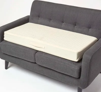 A cream-colored sofa cushion is placed on a gray sofa.