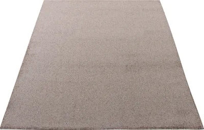 A plain beige rug is shown from a slightly elevated angle against a white background.
