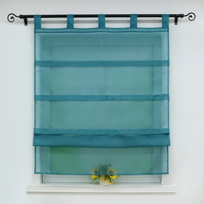 A teal sheer Roman blind hangs on a window rod, covering a window. A small bouquet of yellow flowers sits on the windowsill below.