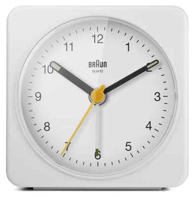 A close-up studio shot of a white Braun analog alarm clock.