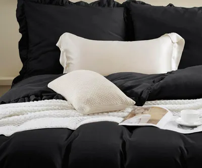 A close-up view of a bed with black bedding and decorative pillows.