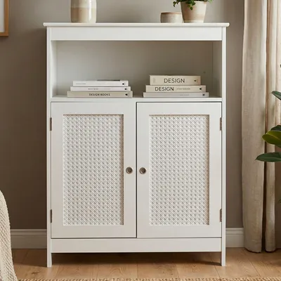 A white cabinet with two doors featuring a woven rattan design, placed in a room setting.