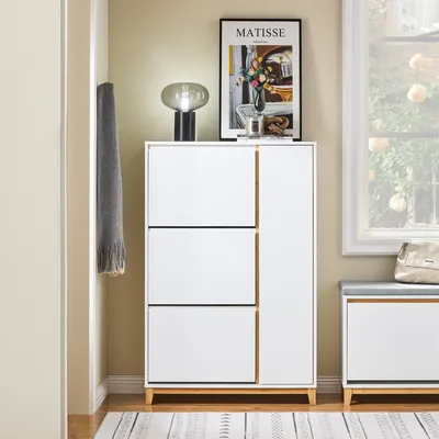 A shoe cabinet with a lamp and artwork on top, next to a window.