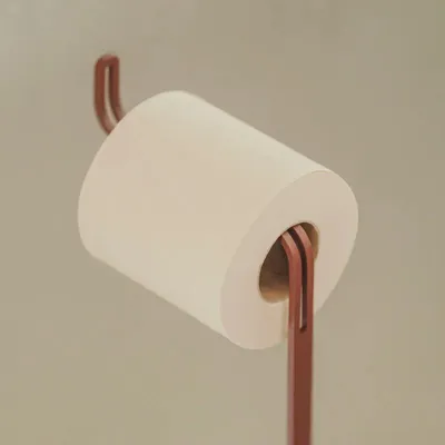 Minimalistischer Toilettenpapierständer MALAGA aus rostbraunem Edelstahl, gezeigt in einer Detailaufnahme mit einer aufgesteckten Papierrolle.