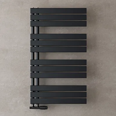 A black radiator against a textured gray wall.