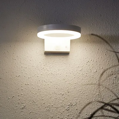 A modern white wall-mounted light fixture with a circular top and a rectangular base.