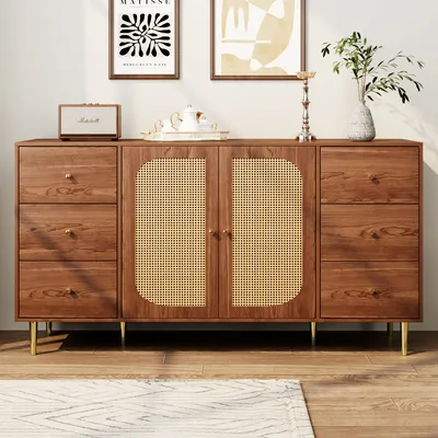 A wooden sideboard with rattan doors and gold legs, displayed in a room with artwork on the wall.