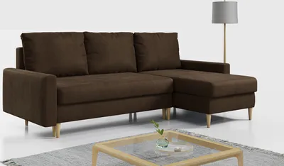 A brown sectional sofa with a chaise lounge is shown in a studio setting with a floor lamp in the background.