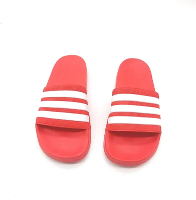 A pair of red Adidas Adilette shower slides with white stripes, presented on a white background.
