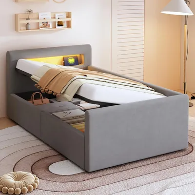 A modern bedroom with a grey upholstered bed featuring a lifted mattress revealing storage space and LED lighting.