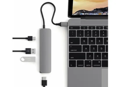 A Satechi USB-C multiport adapter is connected to a laptop, with various cables and a USB drive shown nearby.
