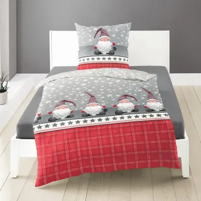 A bed with bedding featuring gnomes and a red plaid pattern.