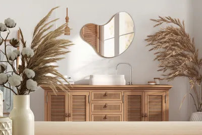 A bathroom vanity with a sink and mirror, decorated with dried plants.