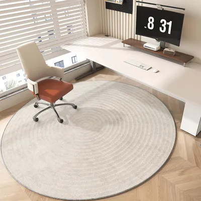 A modern office space with a desk, chair, and a round rug.