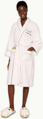 A woman wearing a white bathrobe and slippers.