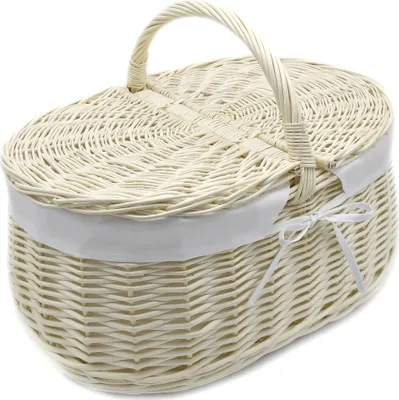 A white wicker picnic basket with a lid and handle, tied with a white ribbon.