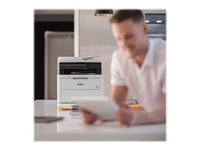 A man is using a tablet in front of a Brother printer.