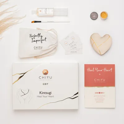 A flat lay of a Kintsugi repair kit and a decorative heart.