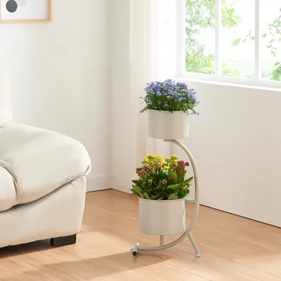 A two-tiered plant stand with two potted plants is placed next to a sofa in a well-lit room with a window.