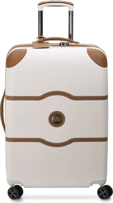 A white and brown Delsey Paris suitcase with a retractable handle and wheels.