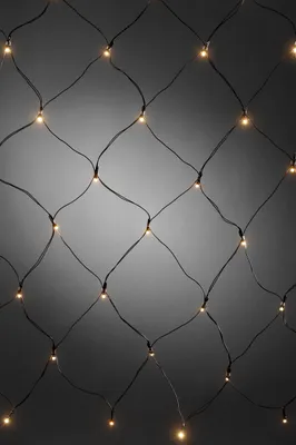 A close-up, full-frame shot of a net of warm white LED lights against a gradient gray background.