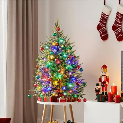 A decorated Christmas tree on a small table, with Christmas stockings and nutcracker figures in the background.