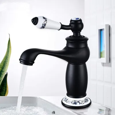 A black faucet with a ceramic handle is shown with water running into a sink.