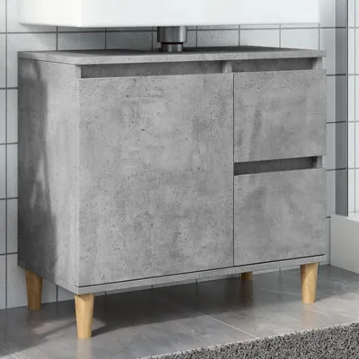 A bathroom vanity cabinet with a concrete-like finish and wooden legs, shown in a tiled bathroom setting.