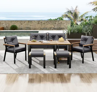 Outdoor patio furniture set with a table, chairs, and stools next to a pool with an ocean view.