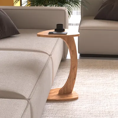 A C-shaped side table with a wooden finish is placed next to a sofa in a living room.