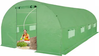 A woman is inside a green greenhouse tunnel, tending to plants.