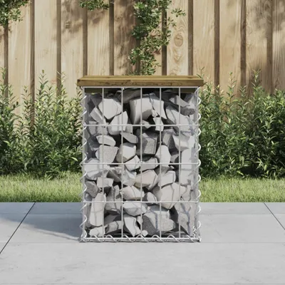 A gabion bench with a wooden top sits on a paved patio, with a wooden fence and greenery in the background.