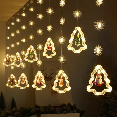 A string of Christmas lights featuring snowflake and Christmas tree shapes with festive figures inside, hanging indoors.