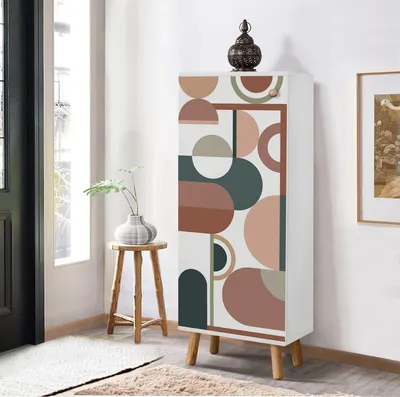A tall, narrow cabinet with a geometric pattern is placed in a room next to a window and a small wooden stool with a vase on it.