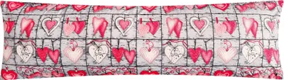 A long pillow with a repeating pattern of hearts and other decorative elements.