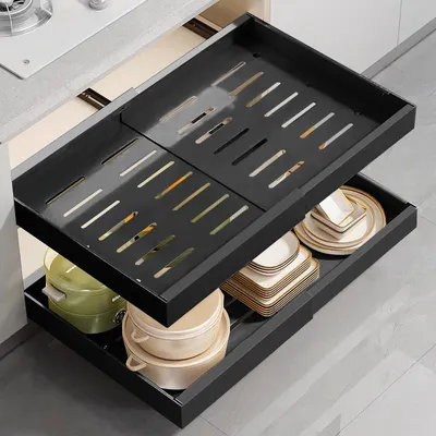 A kitchen drawer with a two-tiered pull-out organizer filled with kitchenware.