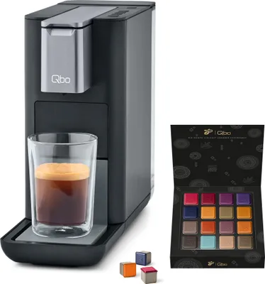 A Tchibo Qbo coffee machine with a glass of espresso and a box of coffee capsules.