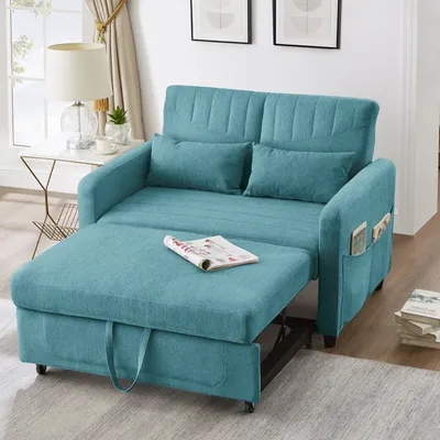 A teal sofa bed is shown in a living room setting, with a side table and lamp to the left, and books to the right.