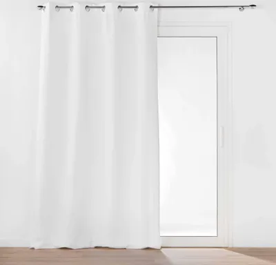 A white curtain hangs in front of a glass door, with a dark curtain rod above.