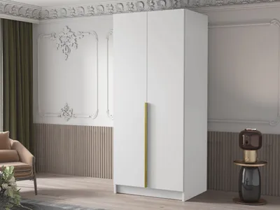 A white wardrobe with a gold handle in a room with decorative wall molding and a chair.