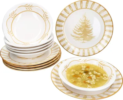 A stack of white bowls with ochre leaf-like decorations and a plate with an ochre Christmas tree design, and a bowl of soup on a plate with ochre stripes.