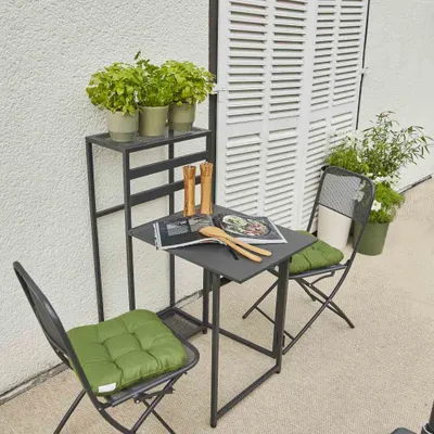 A small bistro set with two chairs and a table on a patio, next to a white shuttered door.