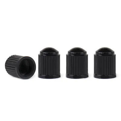Four black valve caps are arranged on a white background. One cap is lying on its side, showing the threaded interior, while the other three stand upright.