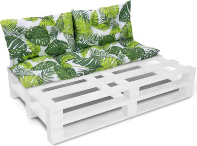 A white pallet sofa with green and white leaf-patterned cushions.