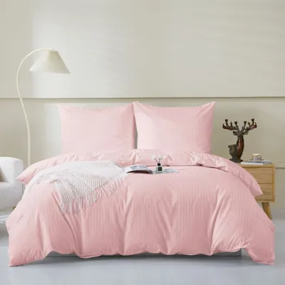 A neatly made bed with pink bedding and a white knitted throw.