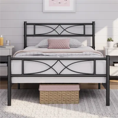 A black metal bed frame with a decorative headboard and footboard, set up in a bedroom with bedding and pillows.