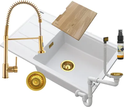 A white kitchen sink with a gold faucet, drain, and accessories, arranged on a white background.